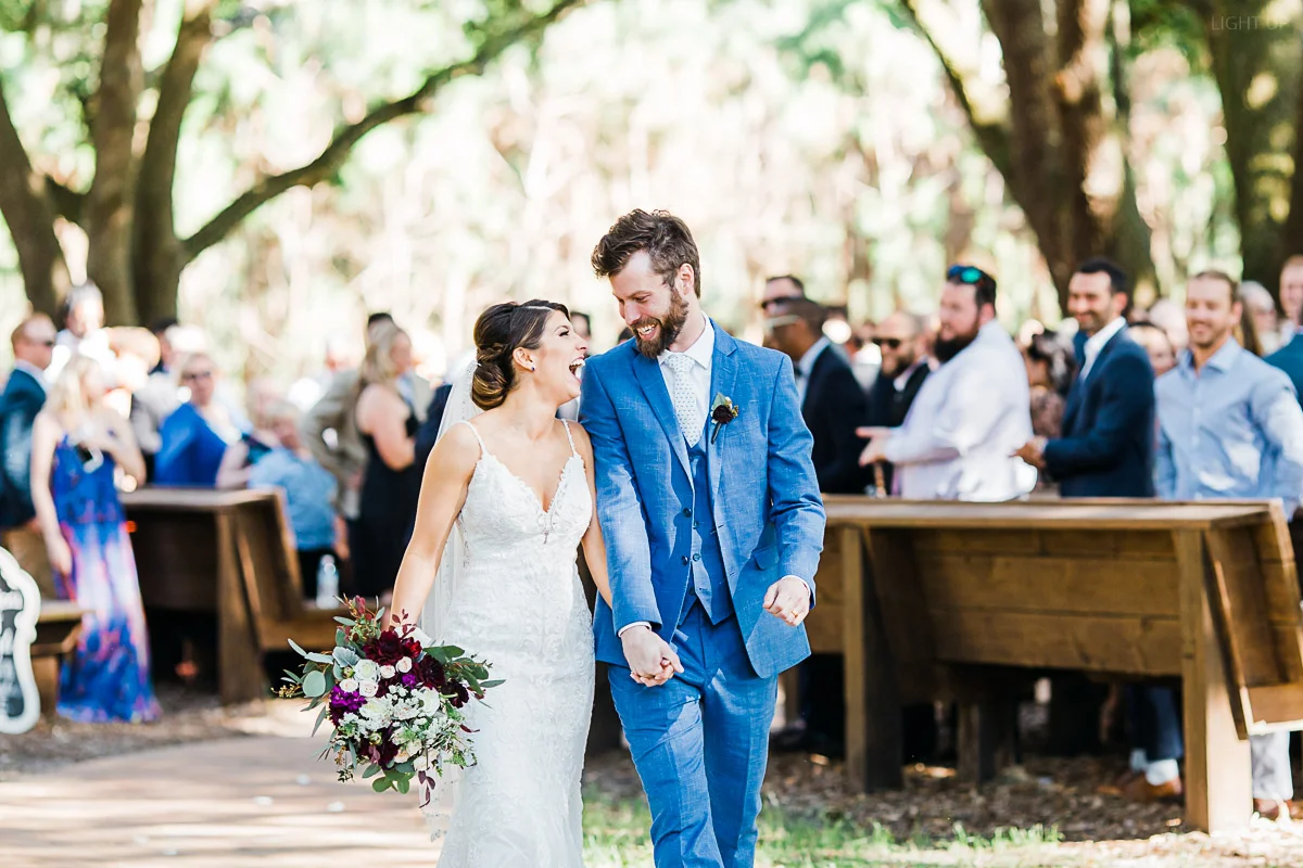 Bride and groom rejoice with intense smiles and laughter at each other as they walk out of the ceremony at Club Lake venue