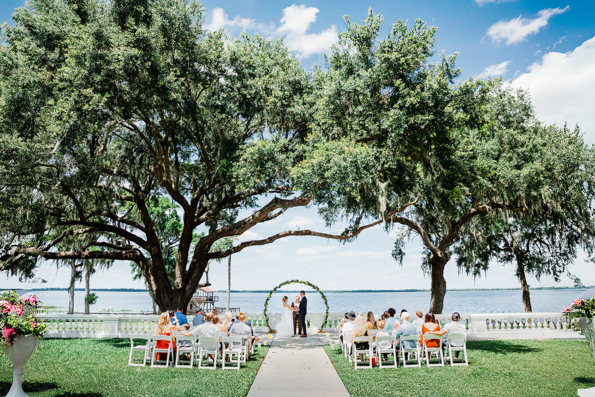 Wedding ceremony with a lakefront view nested in between two large trees at Bella Cosa venue in Lake Wales FL