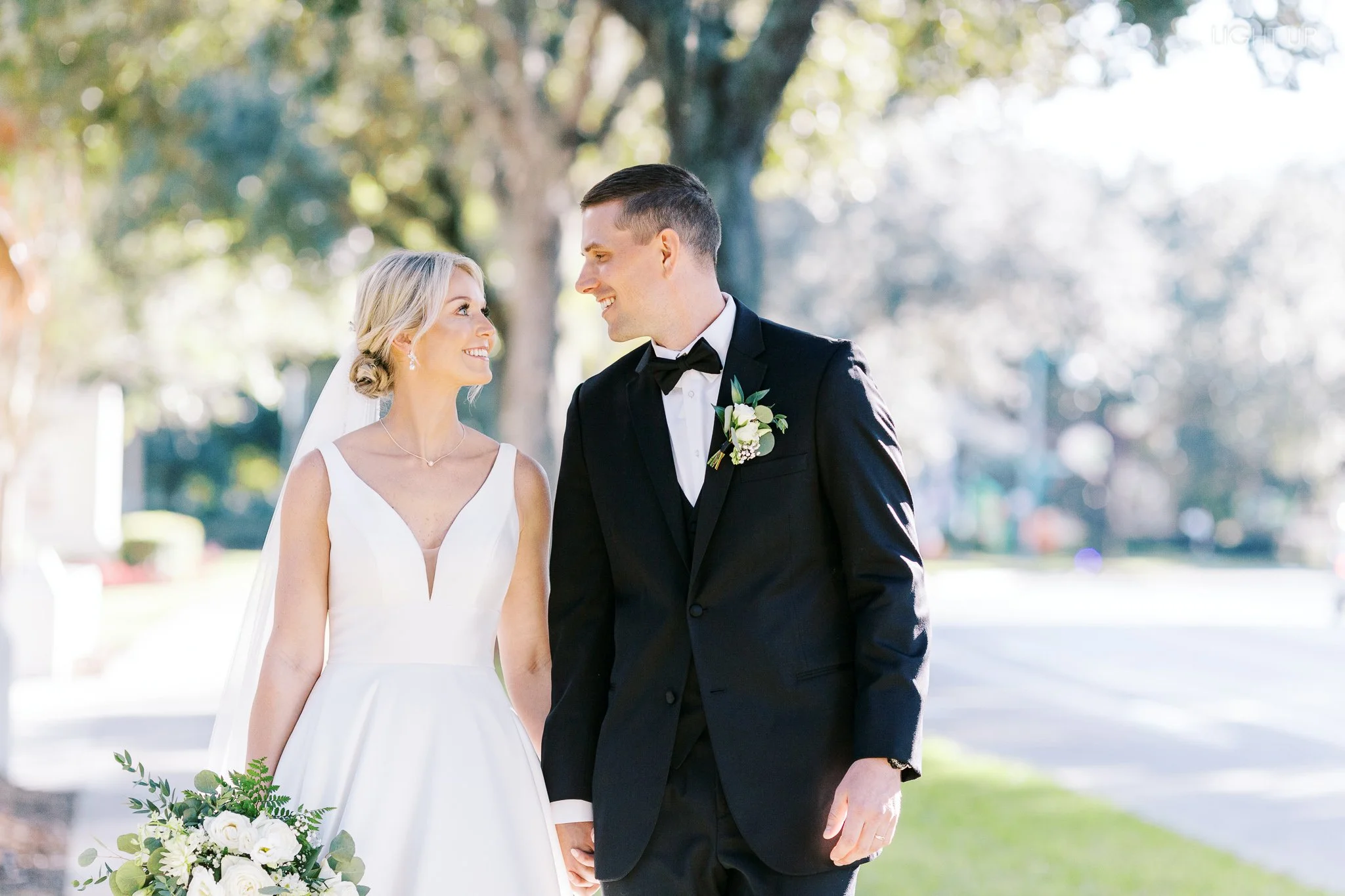 Bride and groom walk together while they hold hands and smile at each other