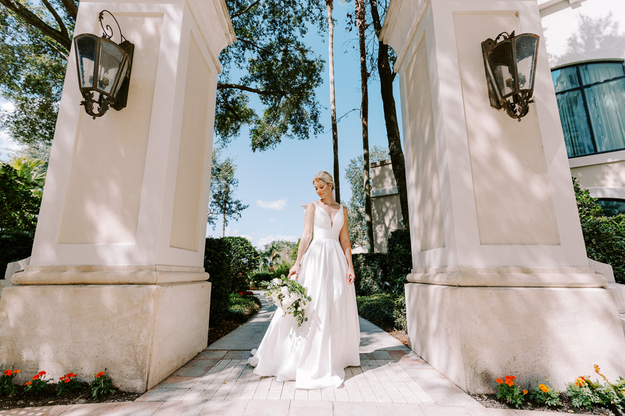 bride holding a wedding bouquet while posing for portrait in between two concrete pillars at Omni Resort Orlando