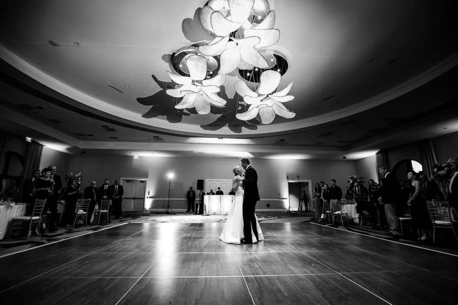 bride and groom dancing under artful lighting fixtures that resemble large flowers