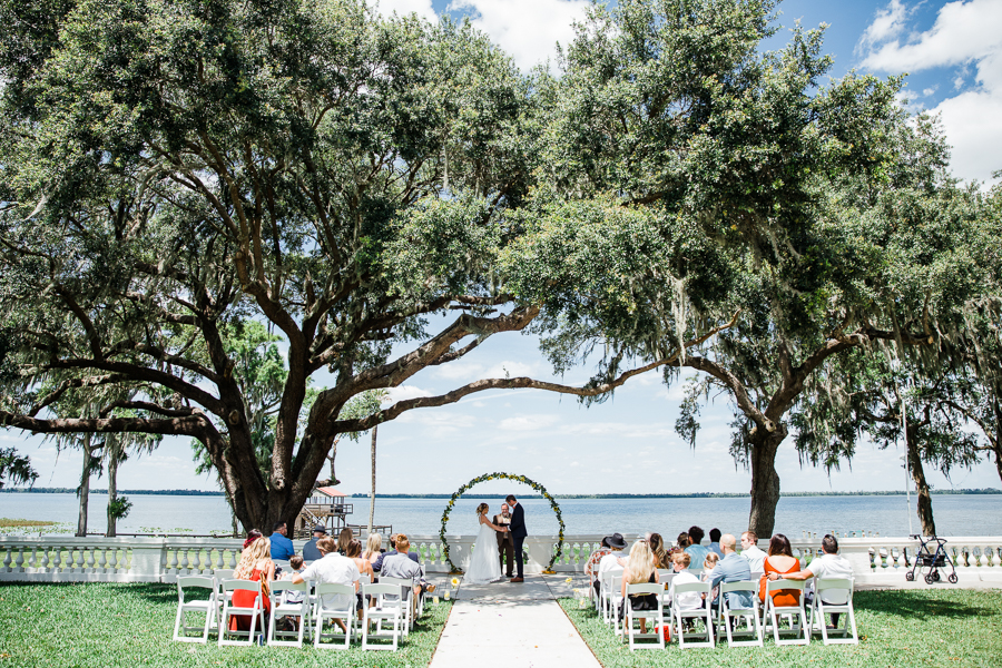 lakeside wedding ceremony with tall trees at Florida wedding venue