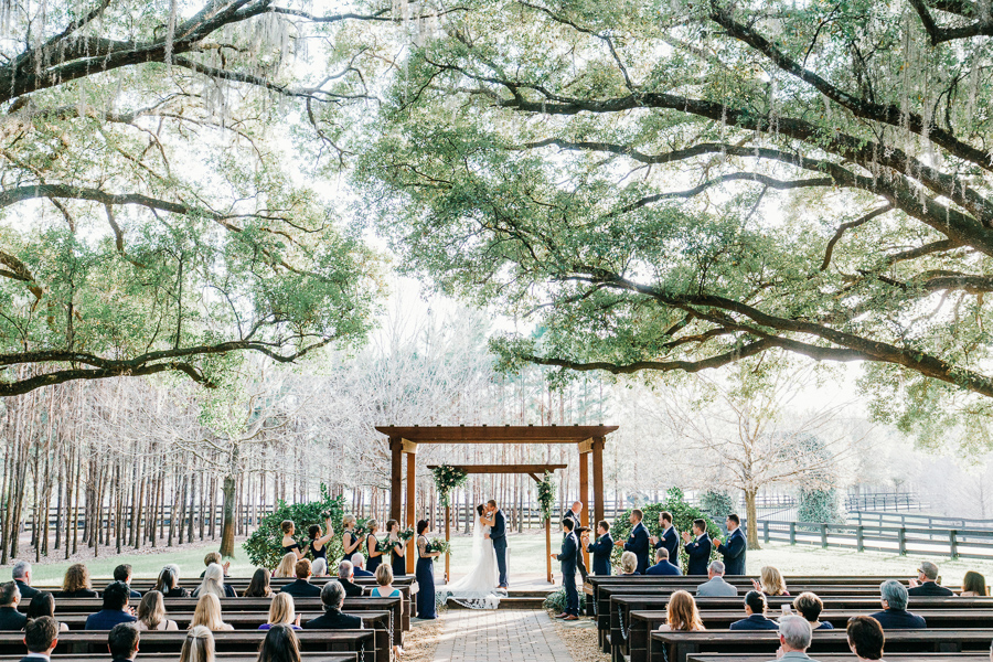 bride and groom share first kiss under a large trees in a Florida wedding venue