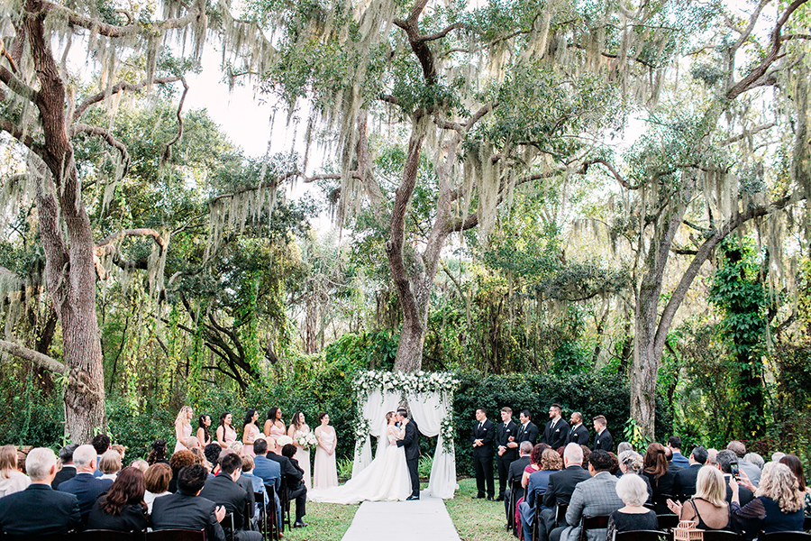 bride and groom kissing during ceremony in a lush garden at a florida wedding venue