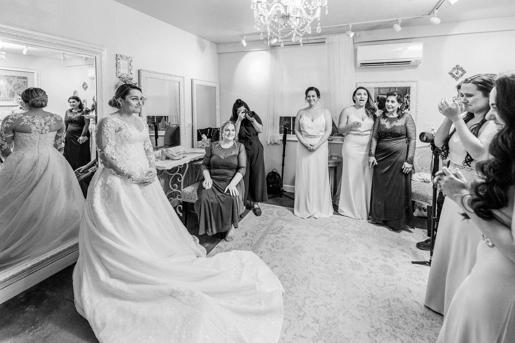 bride smiles at bridesmaids reaction to seeing her for the first time in her wedding dress