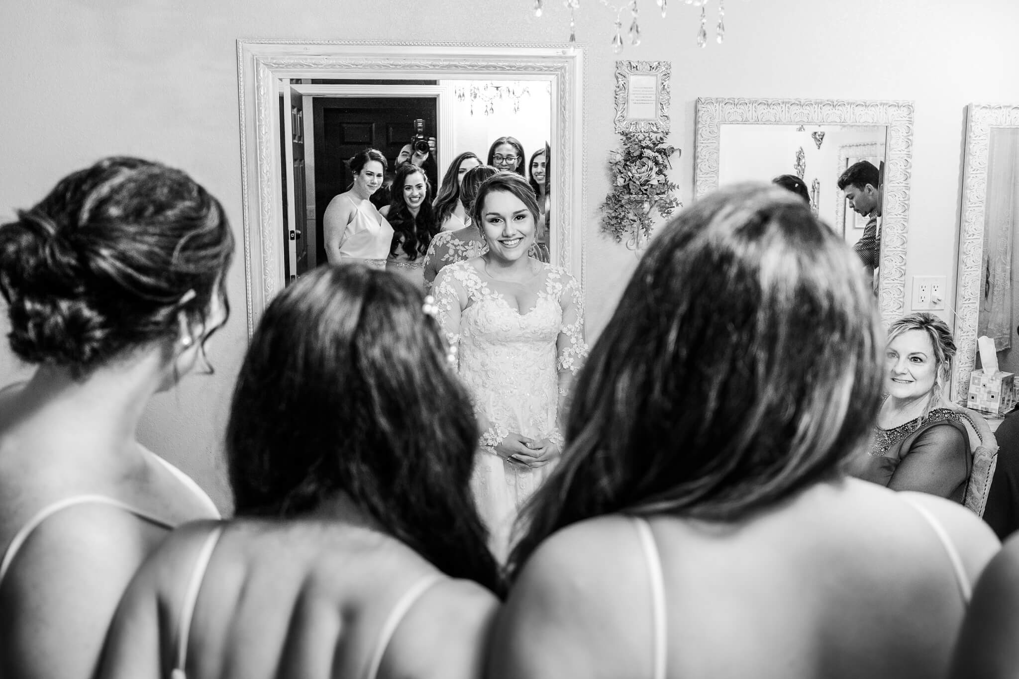 over-the-shoulder view of the bridesmaids perspective seeing the bride in her wedding dress