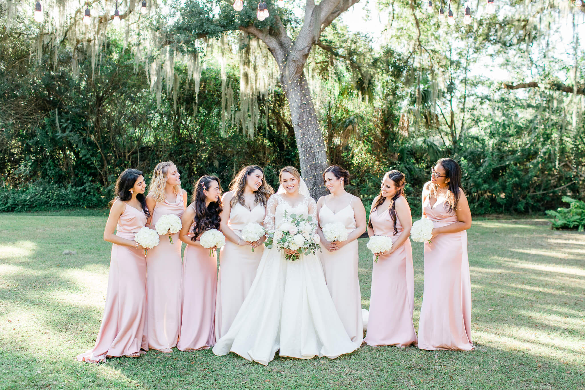 Bride and bridesmaids in pink dresses pose for wedding photos at Bakers Ranch wedding venue