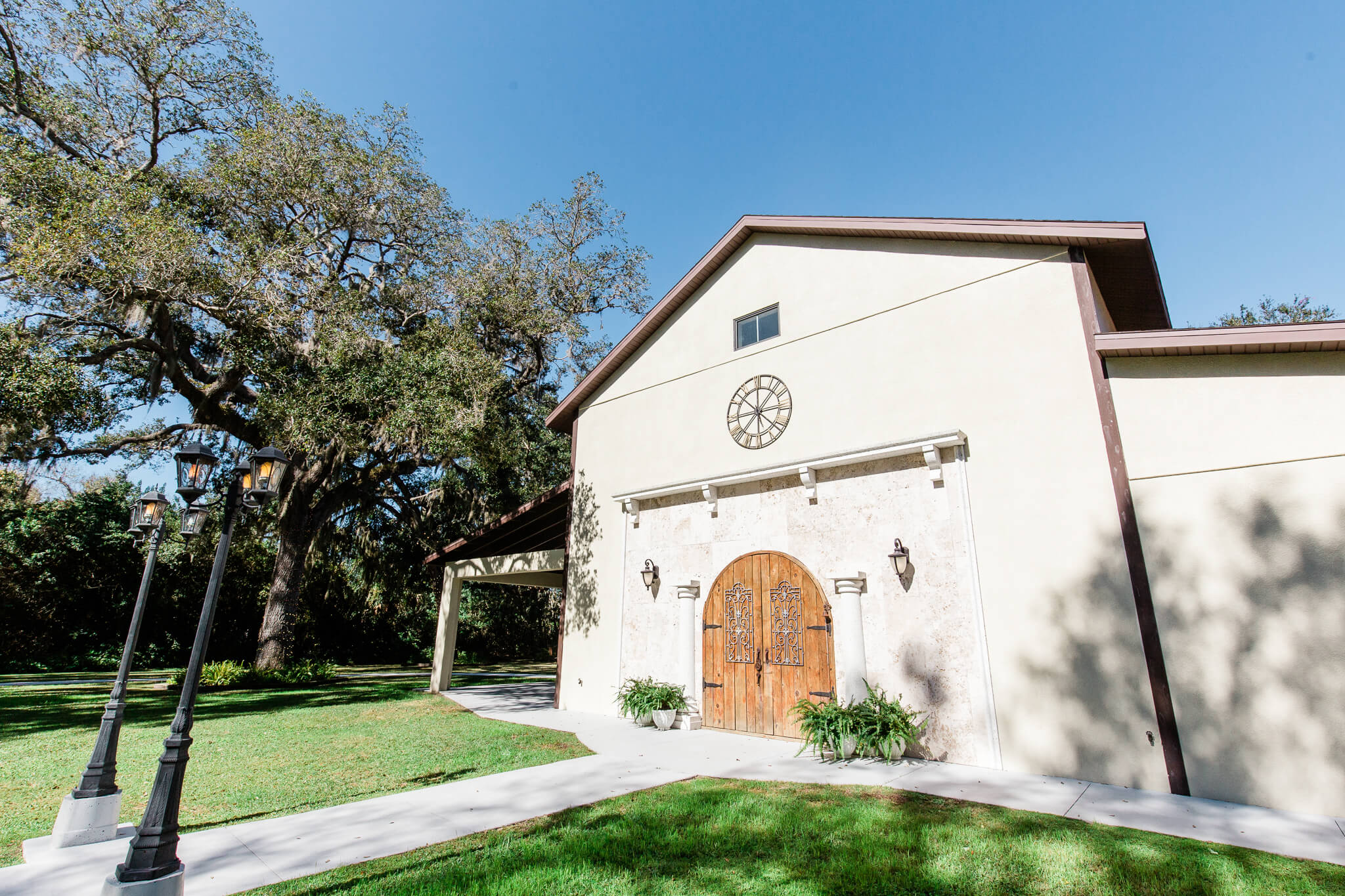 building with a rustic wooden set of doors and iron handles in a lush garden with a blue sky
