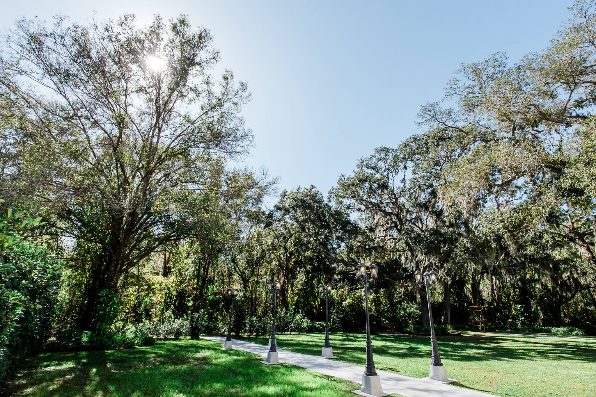 a concrete isle lined with light poles in a lush garden at Bakers Ranch
