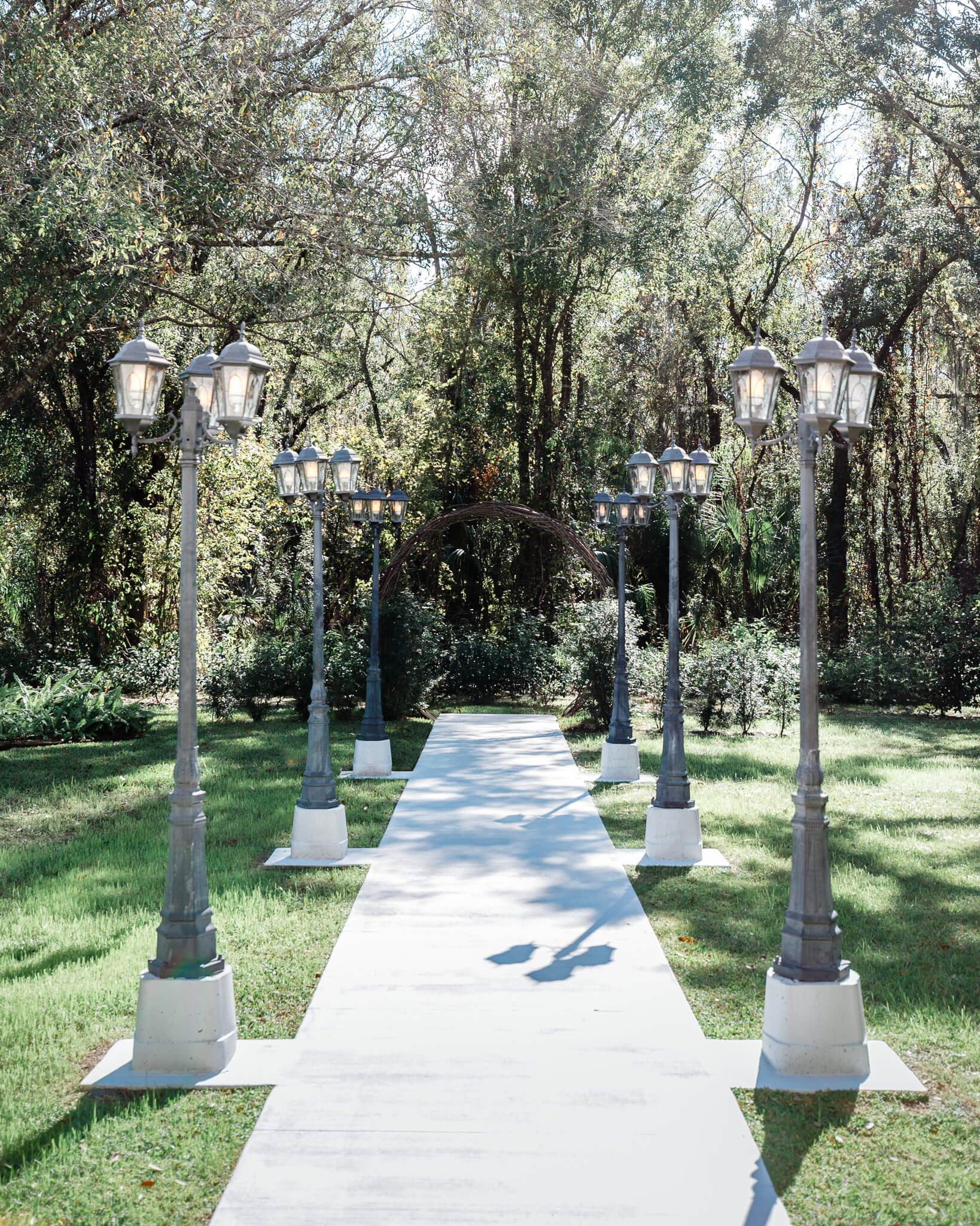 concrete isle lined with street lights in a lush garden