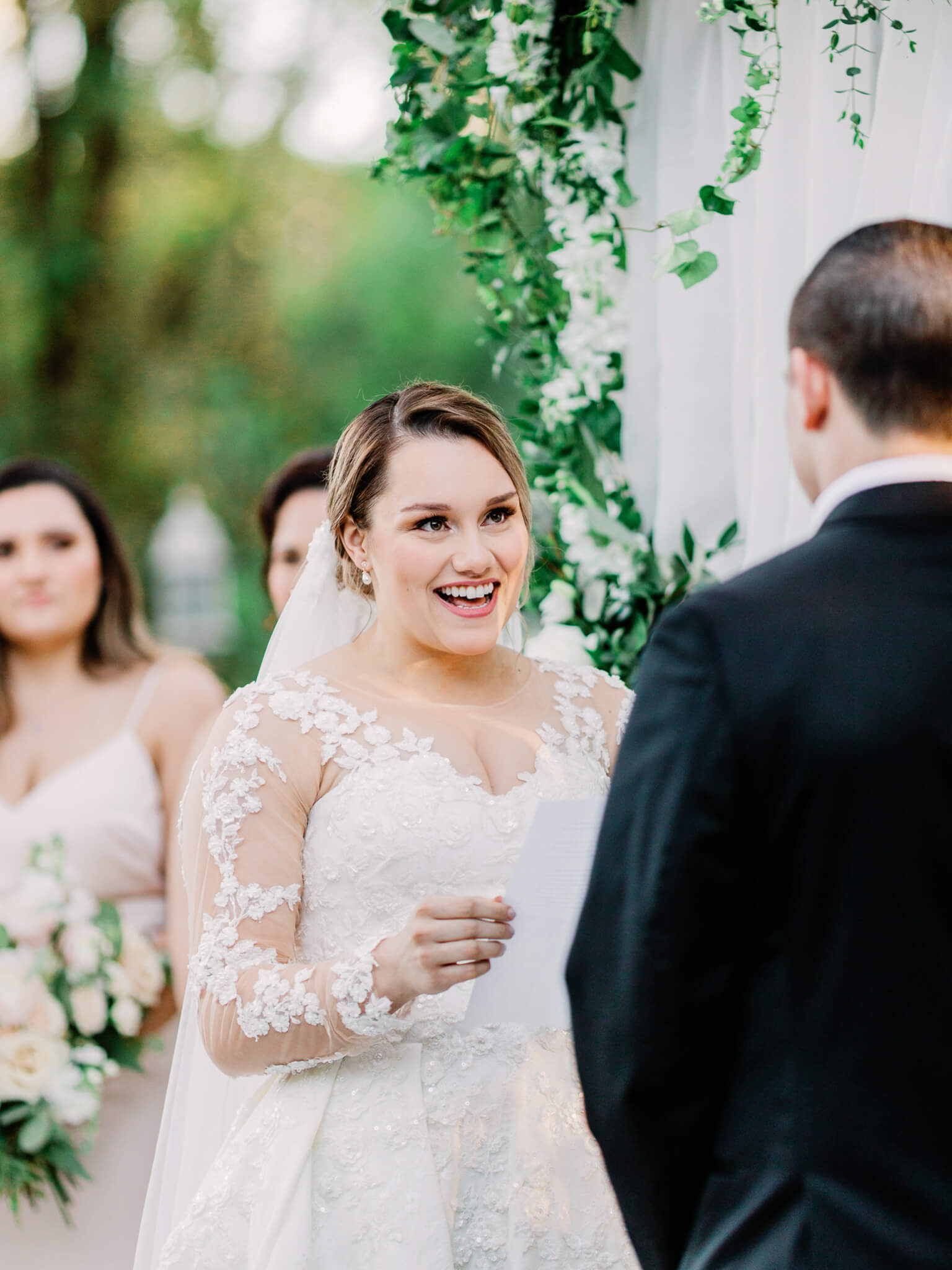 bride smiles while she reads vows to groom during wedding ceremony at Bakers Ranch