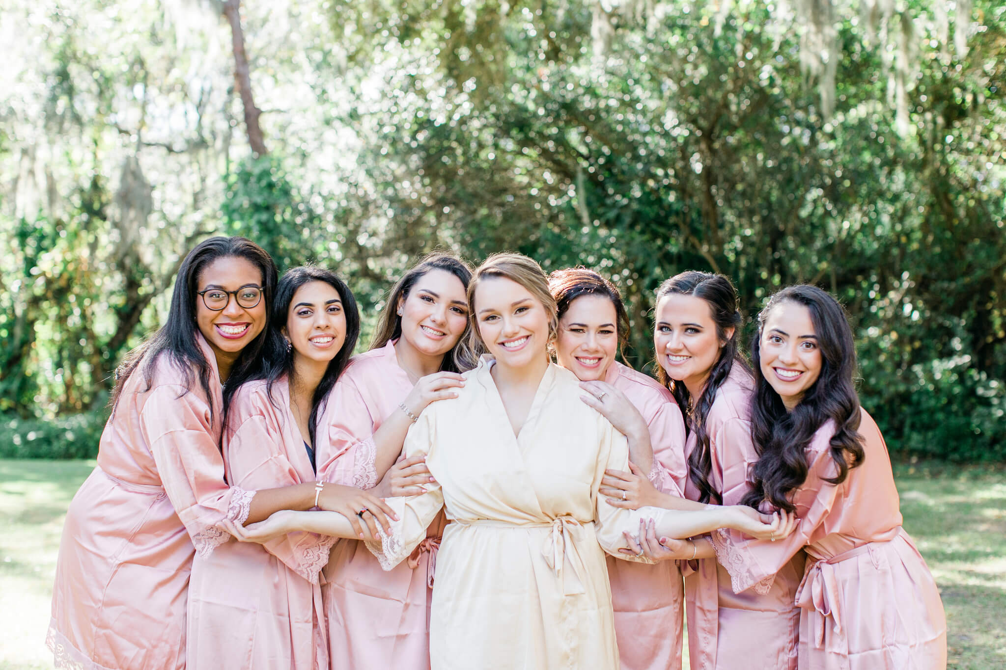 bride and bridesmaids gather close for a getting-ready photo with their matching robes at Bakers Ranch