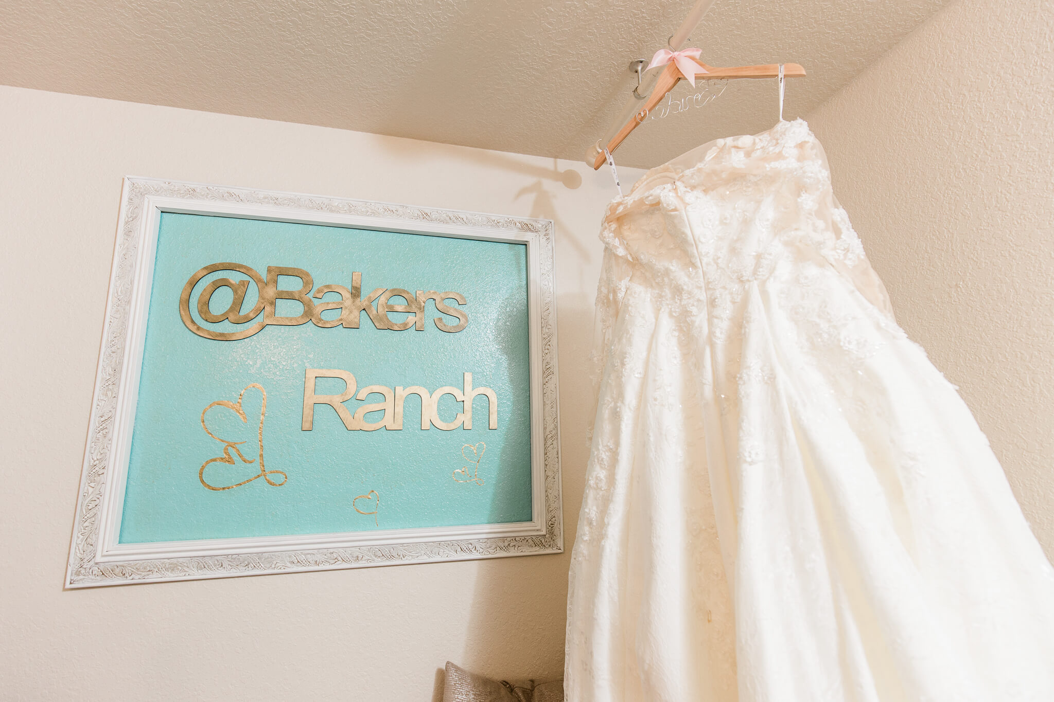 wedding dress hanging in bridal suite next to a sign that says Bakers Ranch