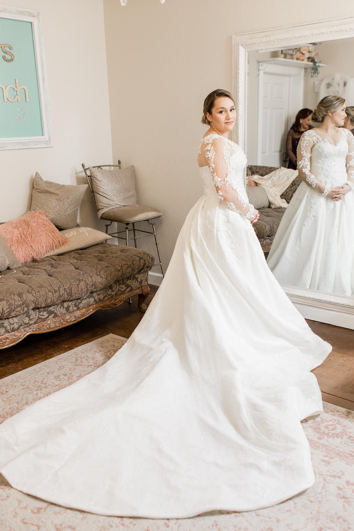 Bride in wedding dress stands in front of full length mirror