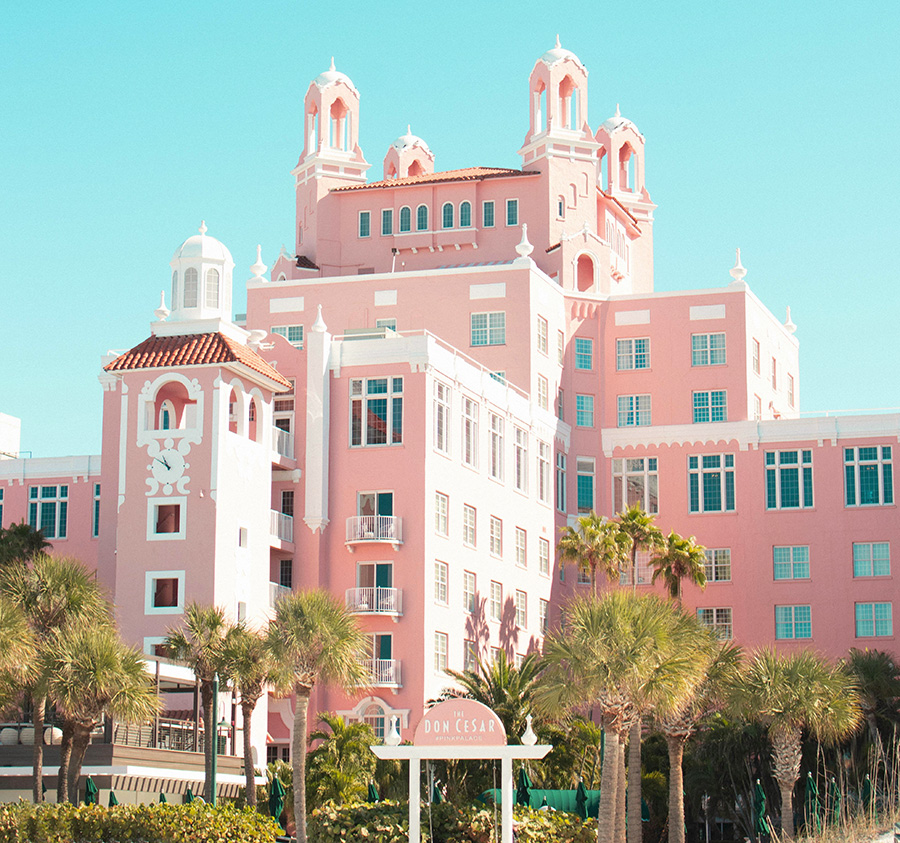 resort style hotel with pink facade and palm trees in the front