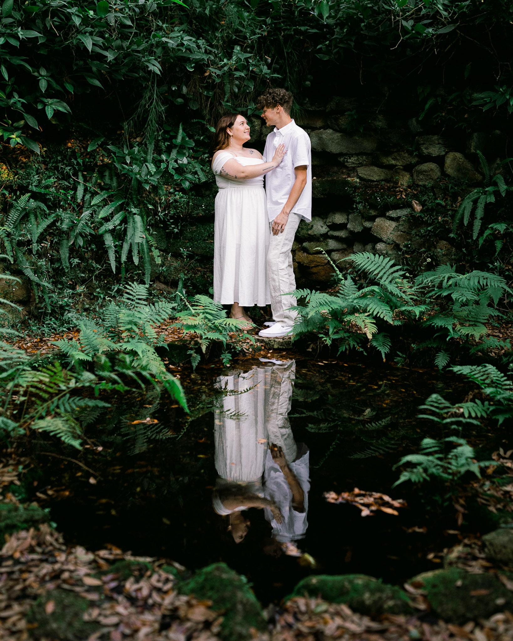 woman places her hand on mans chest as they look into each other with smiles during engagement session at Bok Tower Gardens