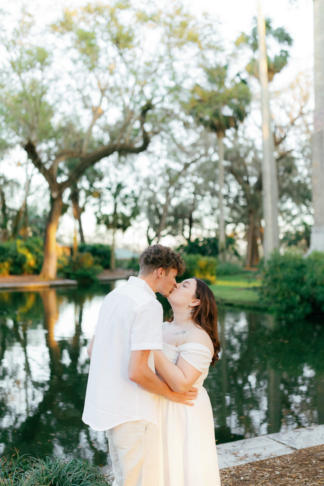 Couple kissing for their engagement photos at Bok Tower Gardens in front of a reflecting pond