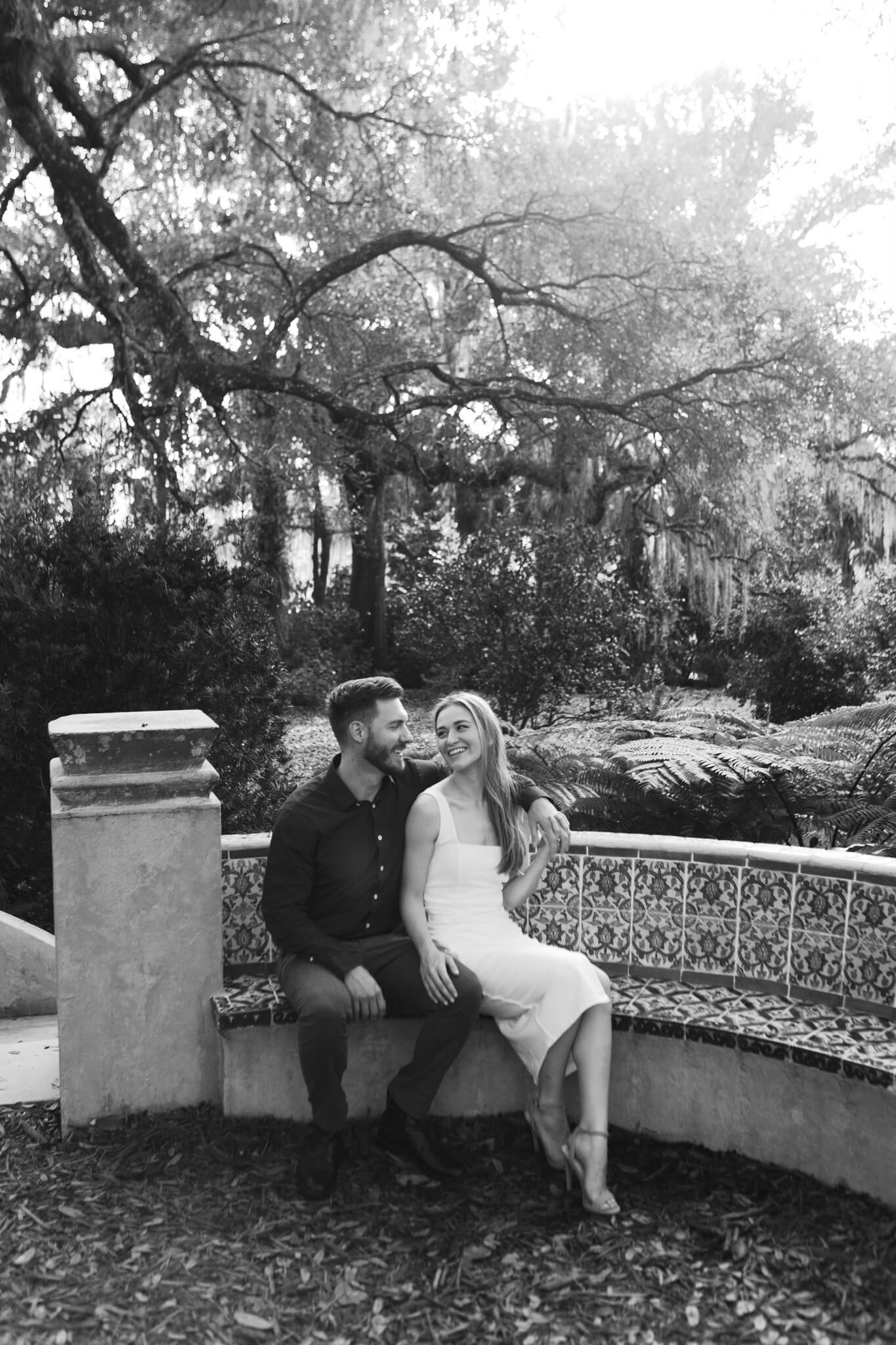 Engaged couple sitting on a curved bench with art tiles at Bok Tower Gardens