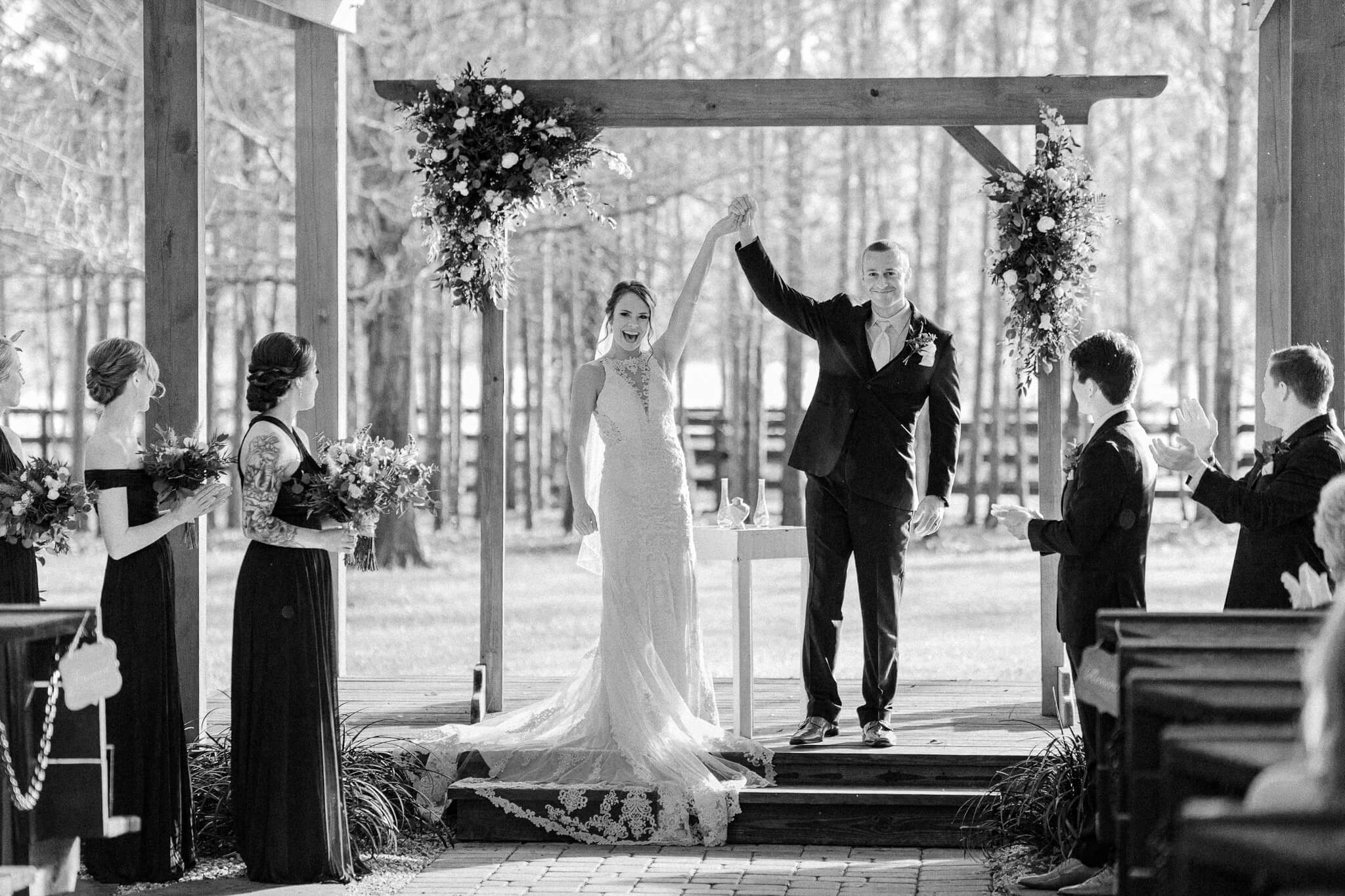 Bride and groom raise their hands together in celebration after getting married at an outdoor wedding venue in Central FL