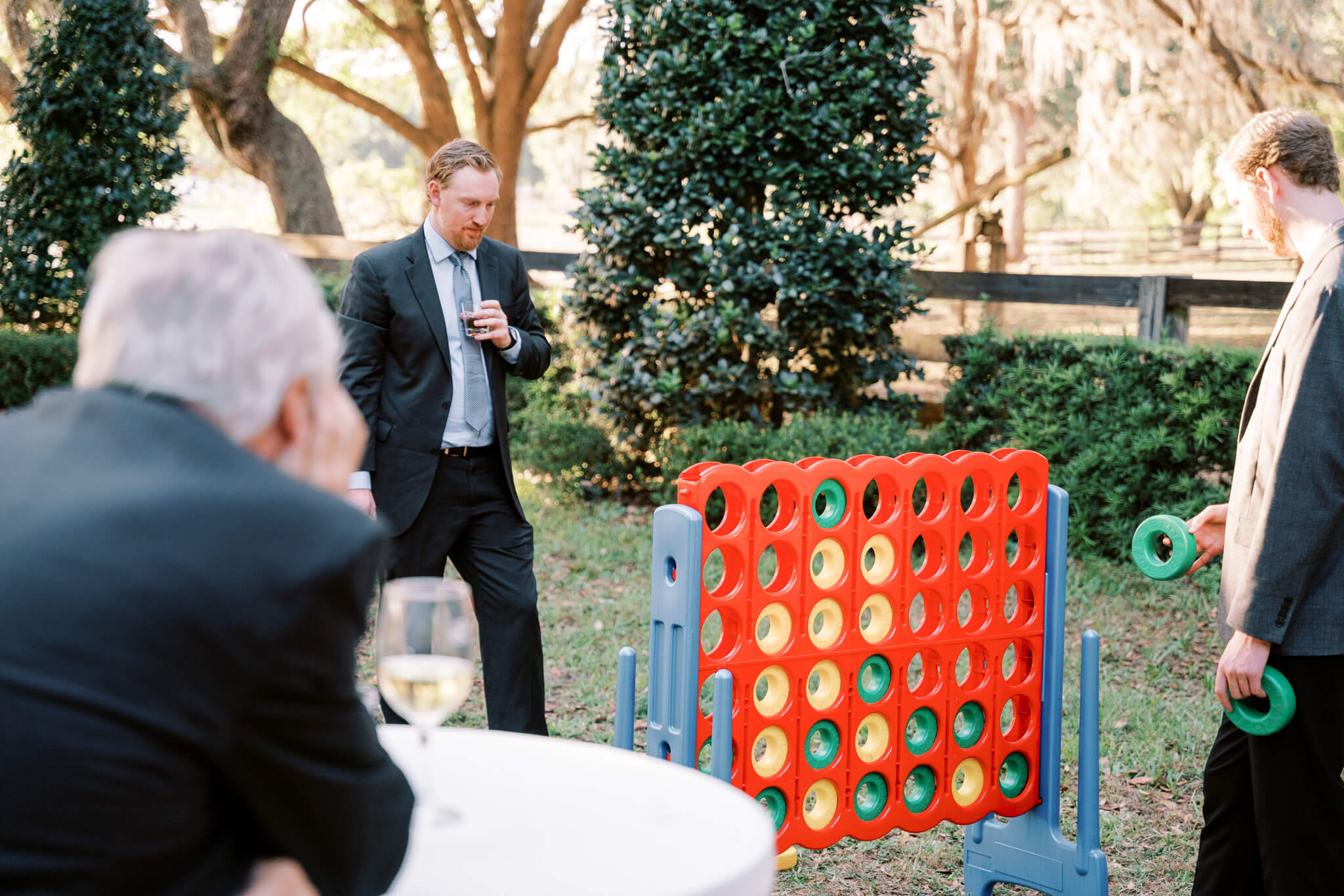 Wedding guest plays connect four during cocktail hour at an outdoor wedding venue in Central FL