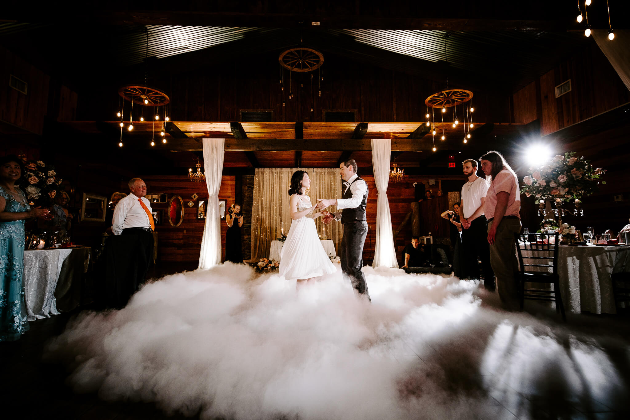 bride and groom have first dance while the floor is filling with fog making it seem like they are dancing on clouds at an outdoor wedding venue in Central FL