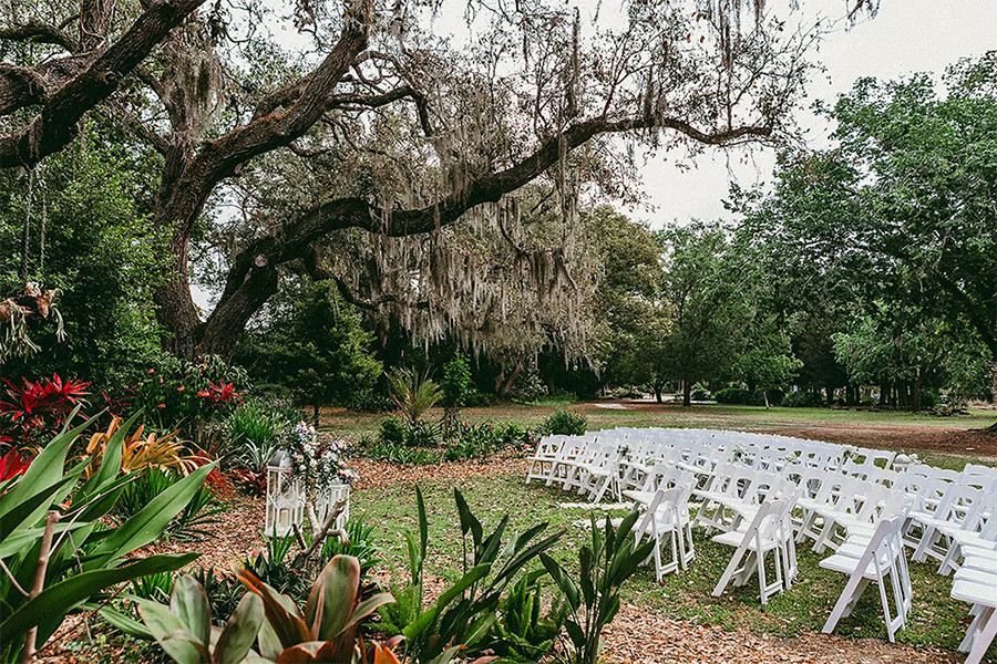 a set of white chairs in a lush garden for a wedding ceremony at an Orlando wedding venue