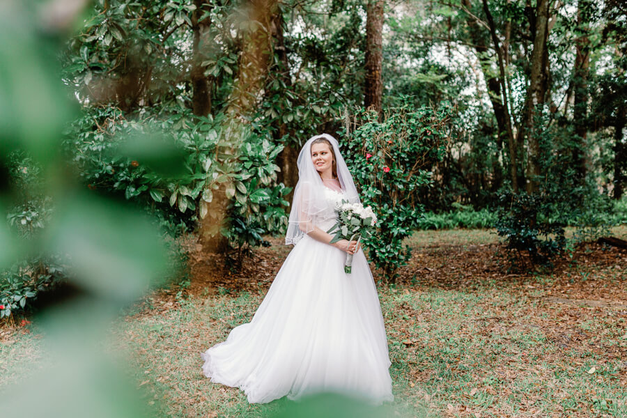Bride holding bouquet poses for wedding photo at The Garden Villa, an Orlando wedding venue with lush gardens