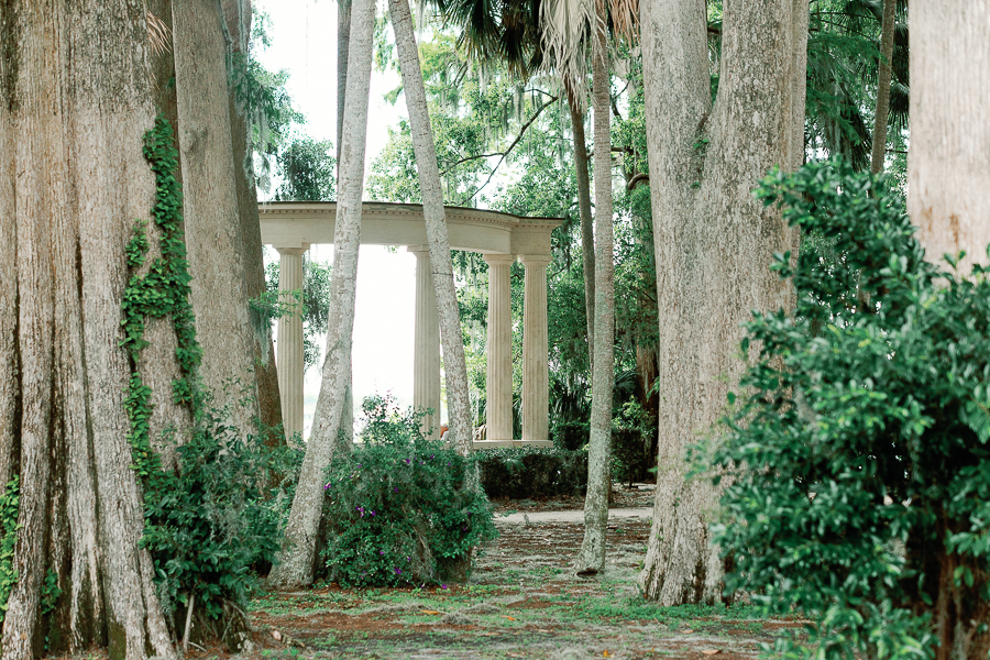 A set of concrete pillars nested in a lush garden with many trees