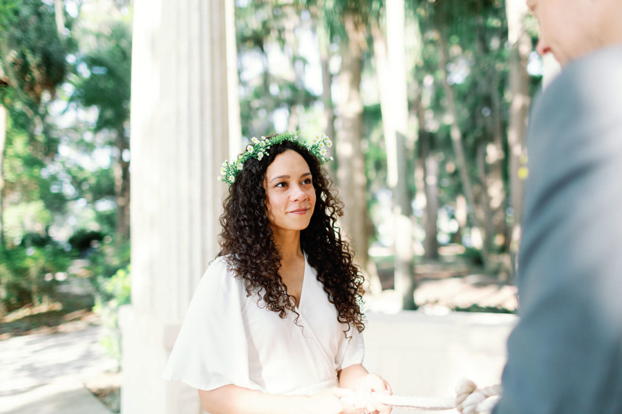 beautiful bride with flower crown looks at groom with a soft smile during a ceremony at an Orlando wedding venue