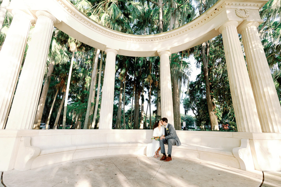 bride and groom kiss in a stunning orlando wedding venue with greek pillars