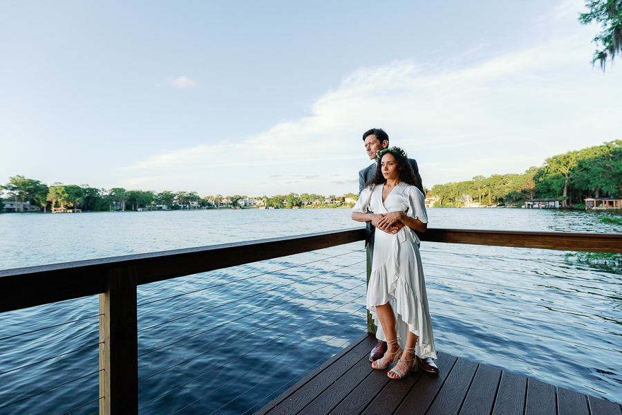 Bride and groom hold each other and stare into the horizon on a lakeside dock at Kraft Azalea, an Orlando wedding venue