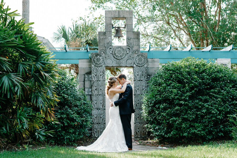 bride and groom embracing with a hug and touching heads under a colonial style doorway with a bell at an Orlando wedding venue