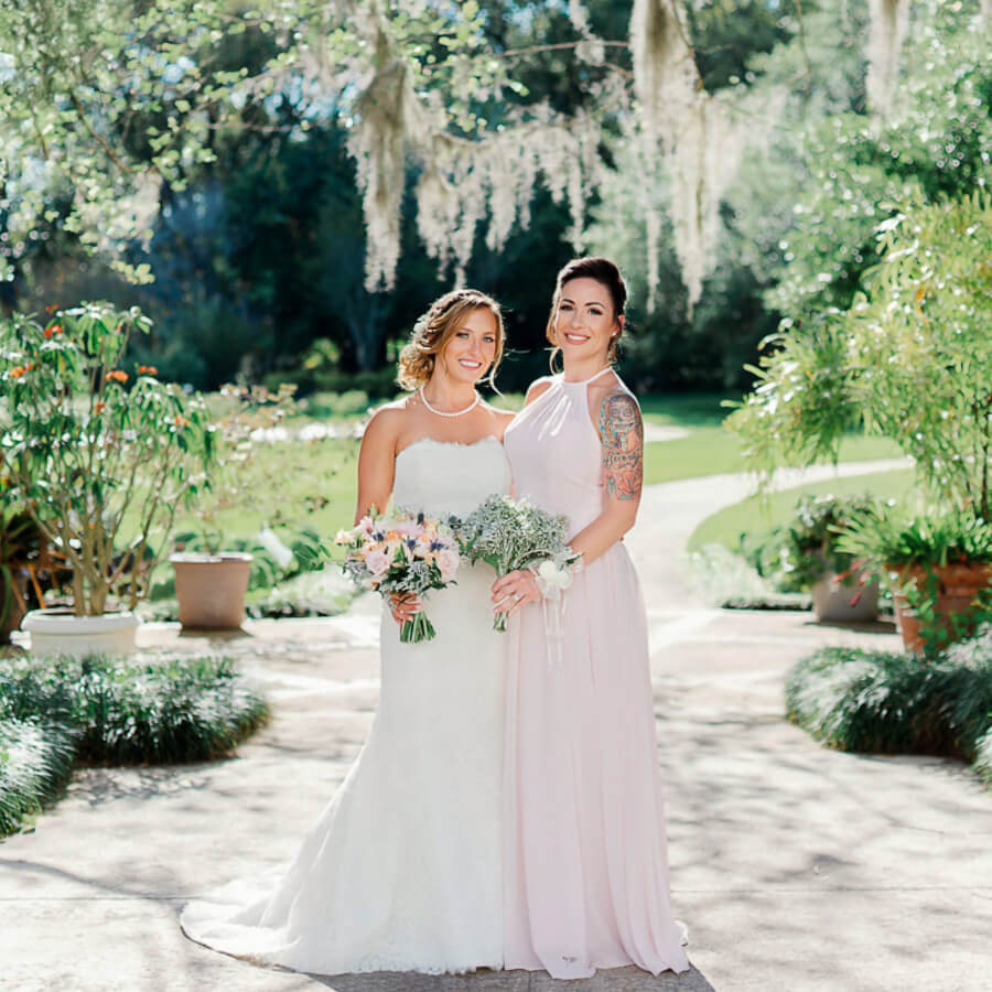bride and bridesmaid in light pink pose for wedding photo in a lush Orlando wedding venue