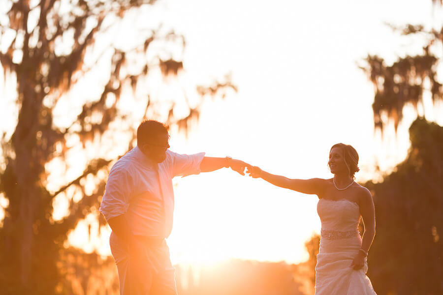 stunning sunset portrait of a bride and groom holding hands at an Orlando wedding venue called Leu Gardens