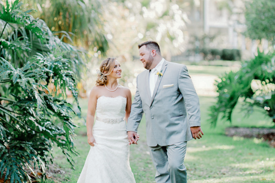 A bride and groom walk through a lush garden at an Orlando wedding venue
