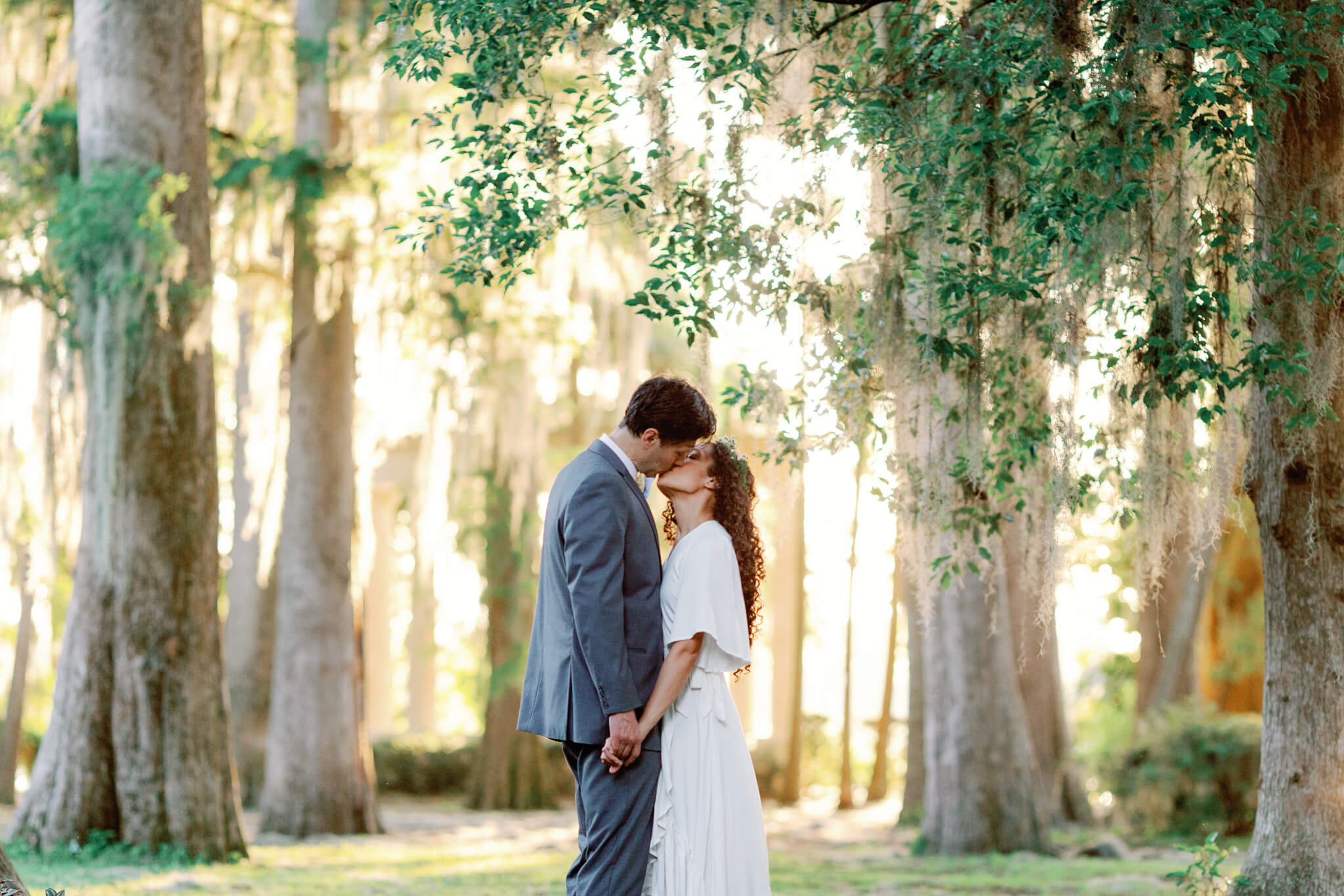 bride and groom kissing at a Florida wedding in a lush garden with tall oak trees