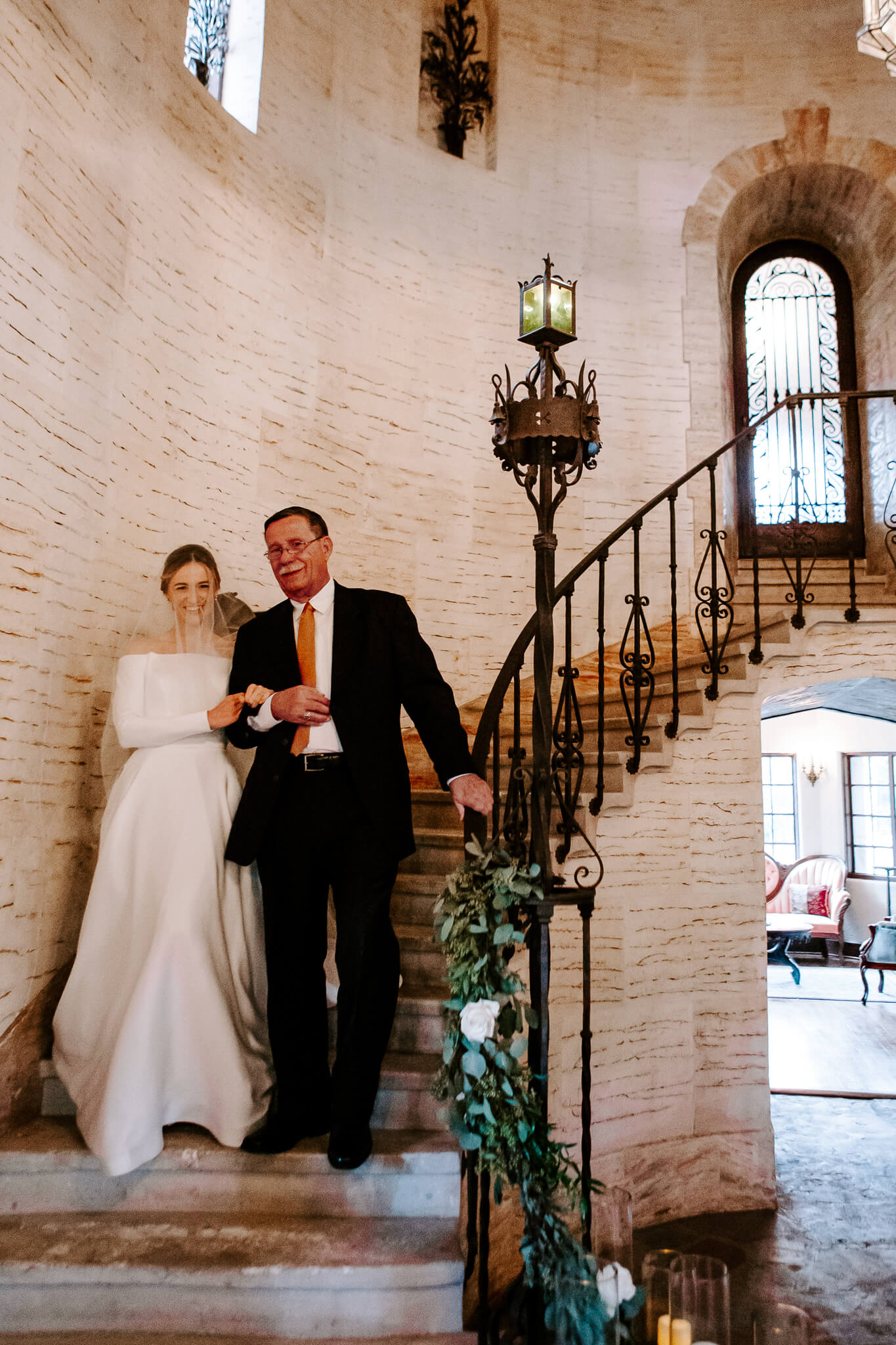 Bride walking down a spiral staircase at the howey mansion alongside her father
