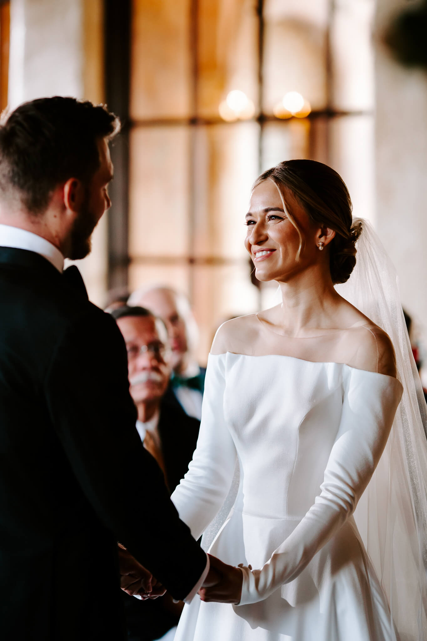 smiling bride looking at groom while holding hands during wedding ceremony at the howey mansion