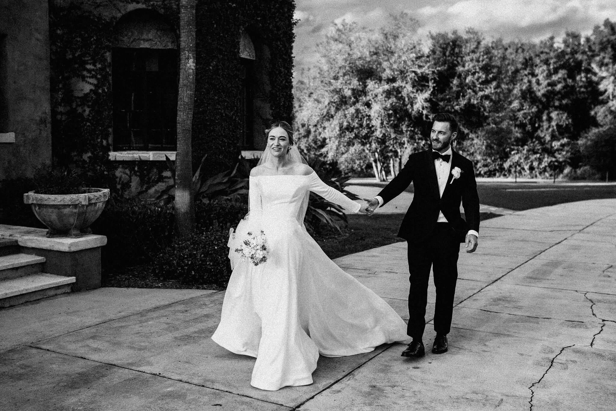 bride in beautiful wedding dress leads the way while holding groom's hand