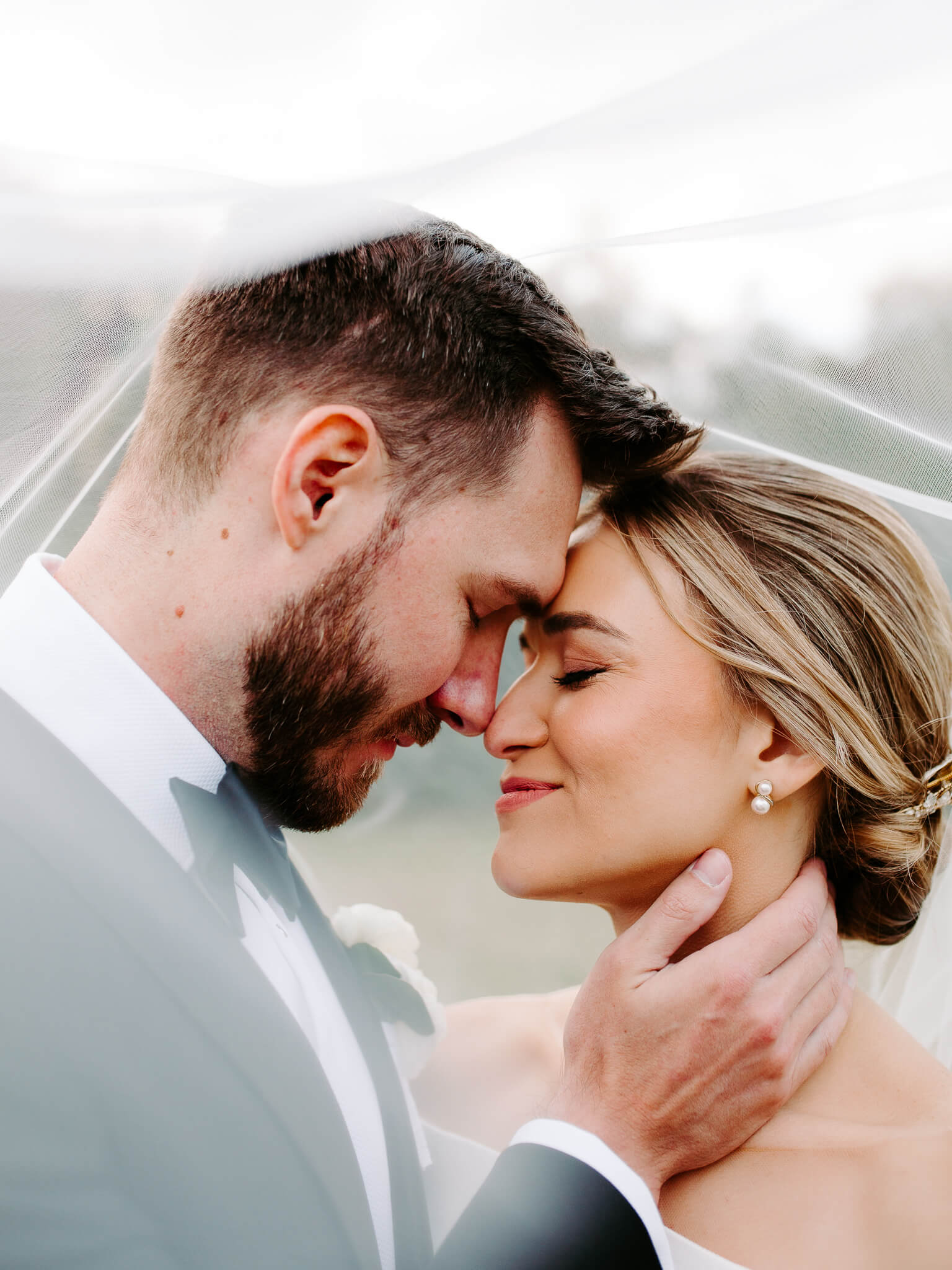 Groom leans his forehead closer to bride's head while they both close their eyes