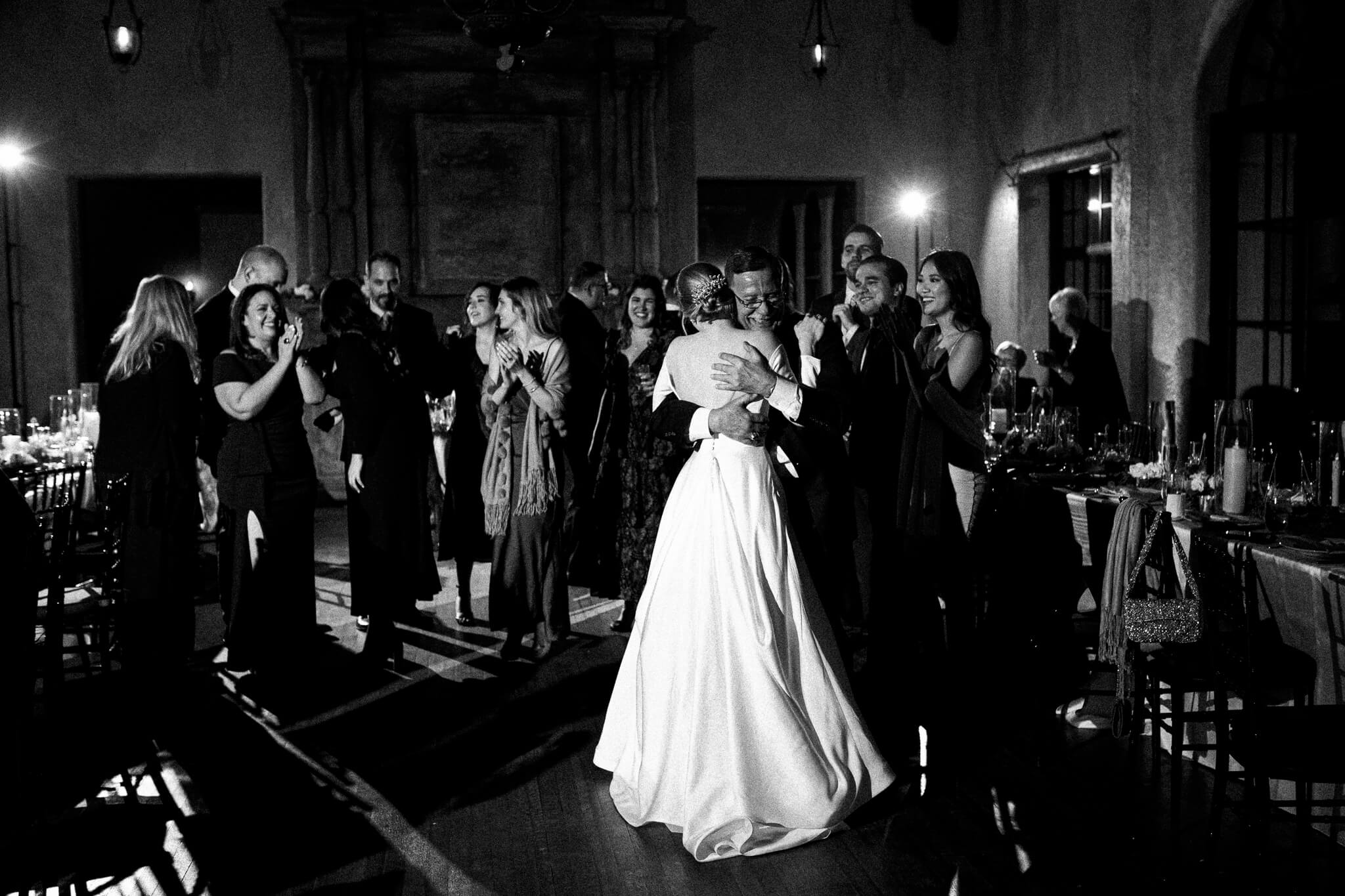 bride is embraced by a hug from her father during a wedding reception at the howey mansion