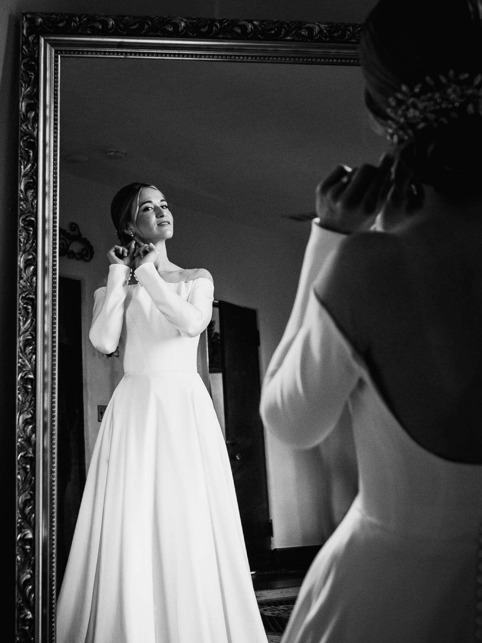 bride in a white wedding dress adjusts her earing while getting ready at the howey mansion