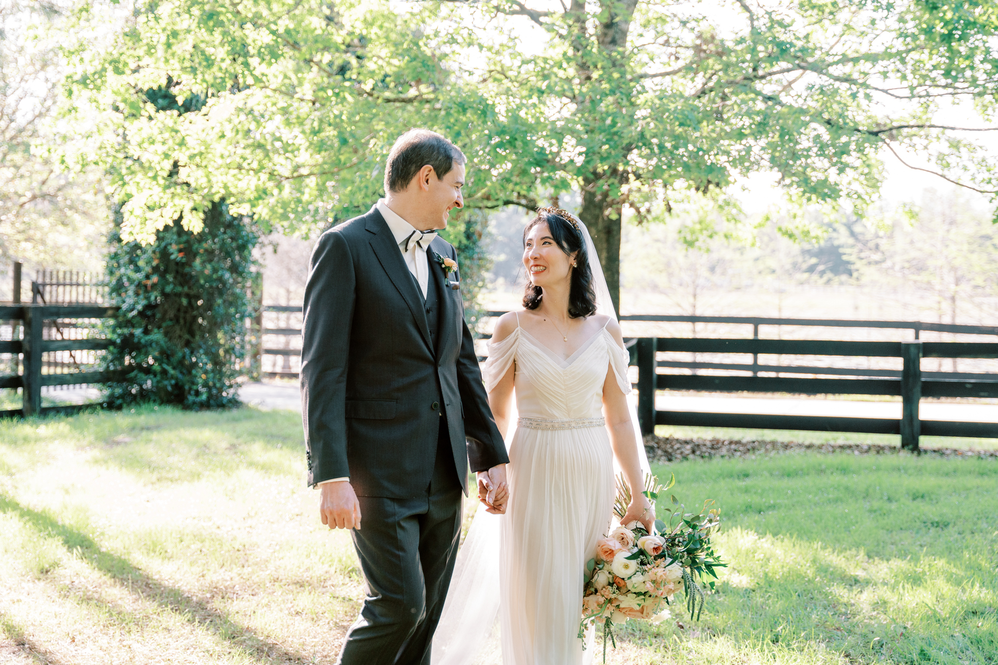 Bride and groom stroll through a lush paddock at Club Lake Venue