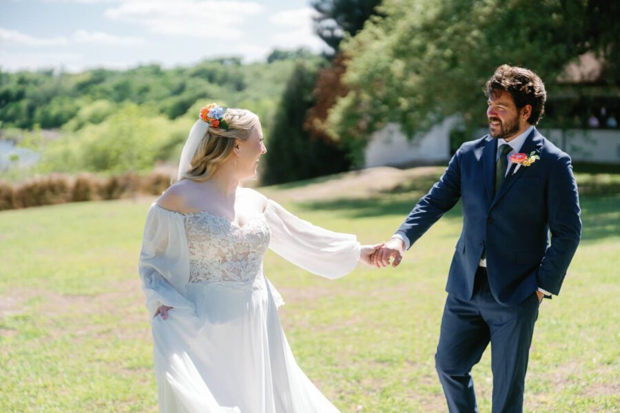 bride holding grooms hand while looking back at him