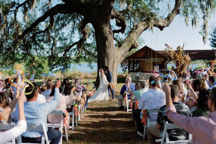 bride and groom share first kiss under at tree
