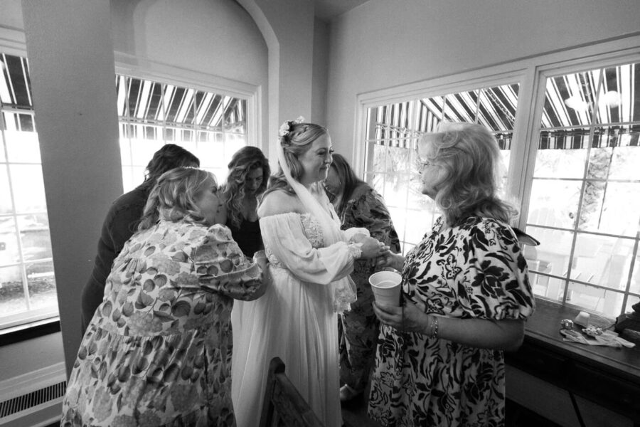 women surround bride to bustle her dress