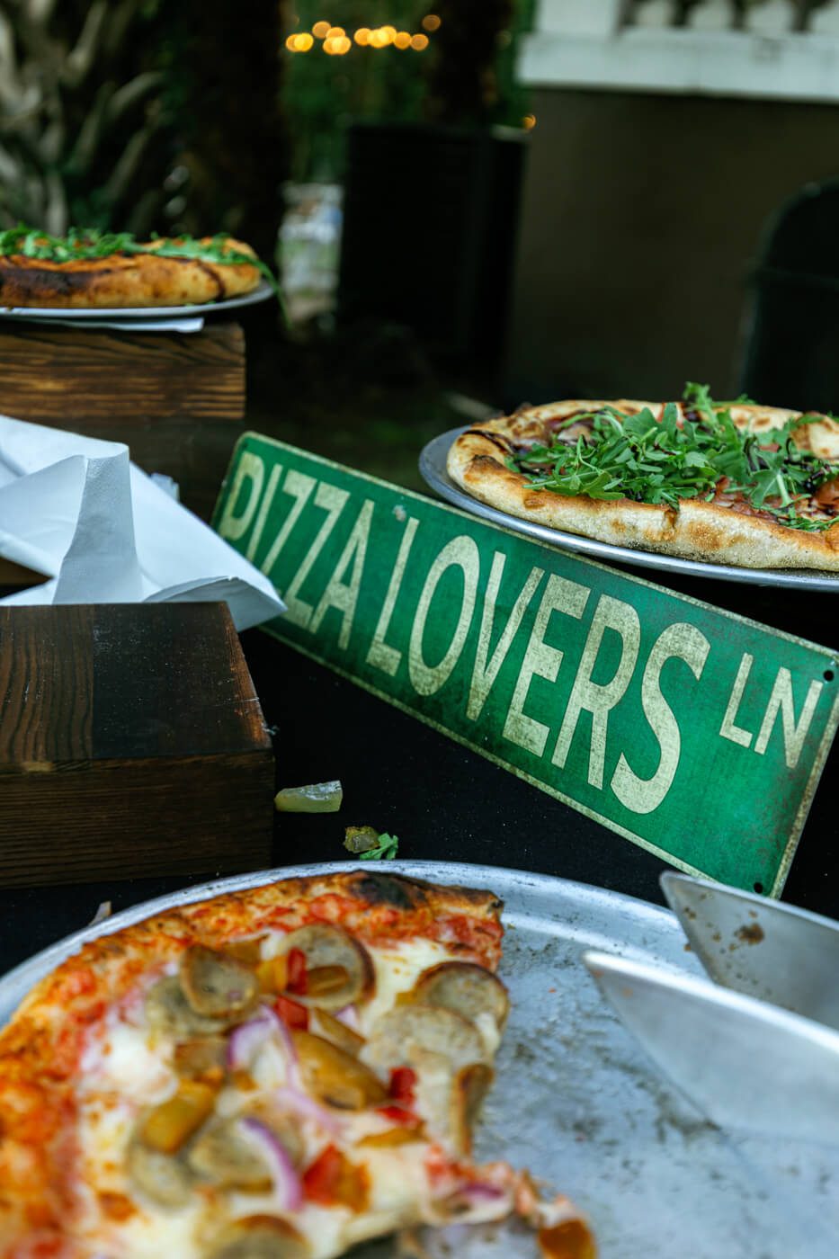 sign that reads "pizza lovers lane" on a table serving pizza