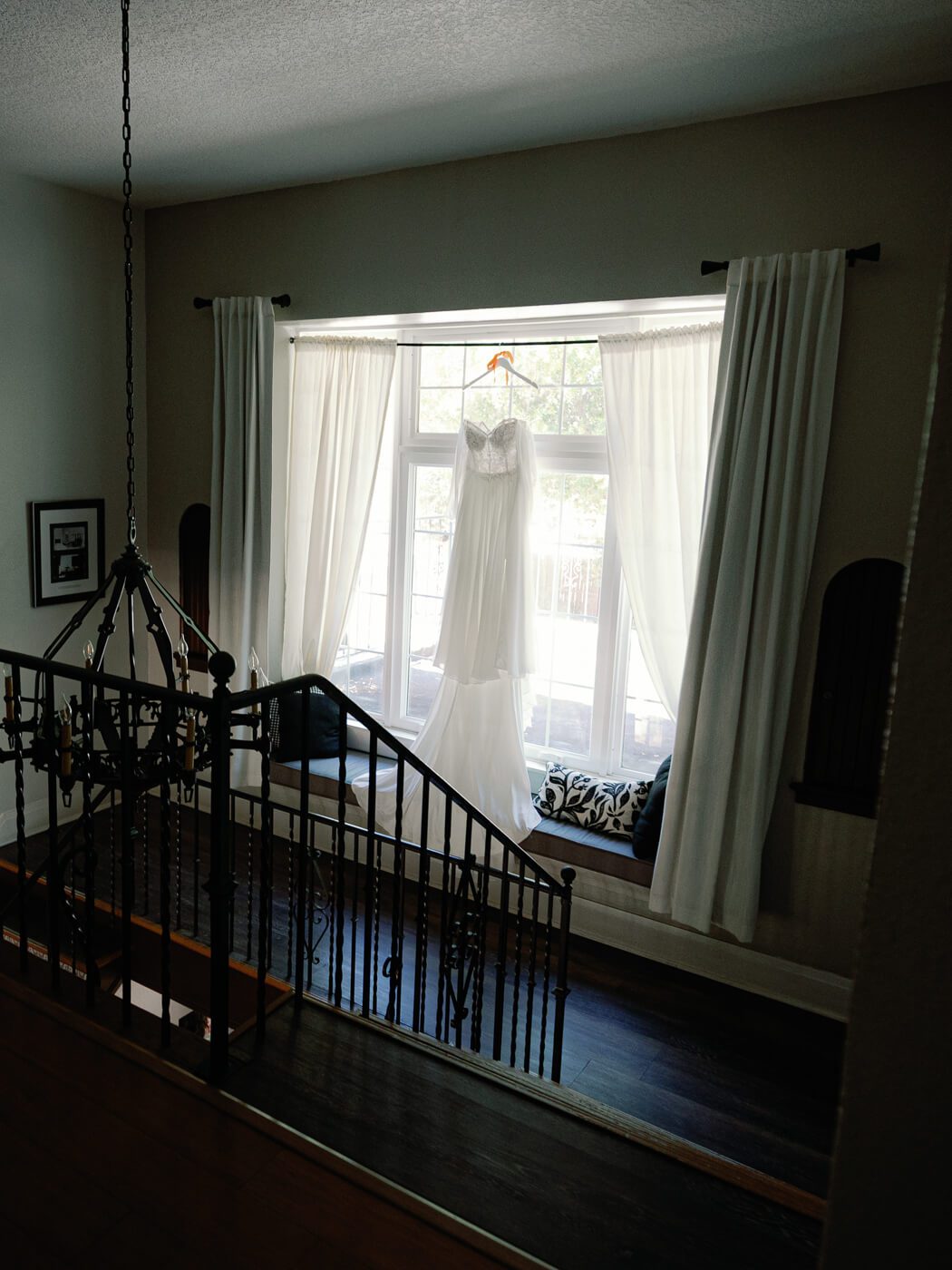 wedding dress hanging in front of a large window at Lake Lucy Estate