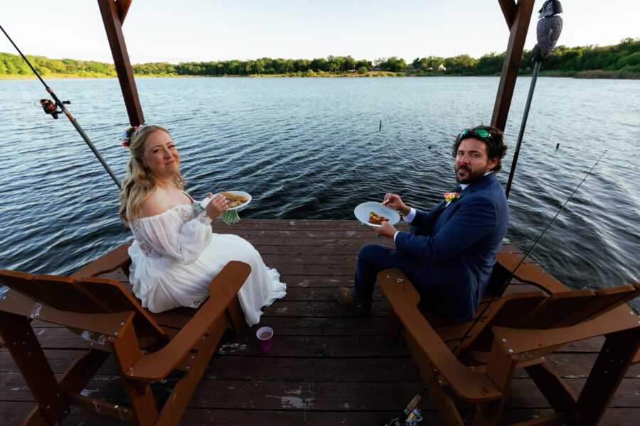 bride and groom sitting for a bite to eat look back at camera with a smile