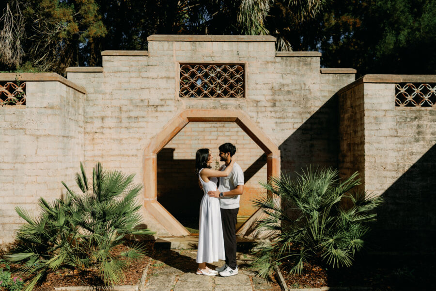 engaged couple posing in front of architectural wall with geometric wall known as the Moon Door at Bok Tower Gardens